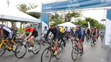 Largada da prova com ciclistas abaixo do portal. Prova é na orla. #paratodosverem