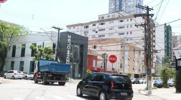 carro atrás de caminhão cruzando uma avenida. #paratodosverem