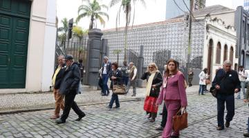 visitantes andam sobre calçamento de rua em frente ao outeiro de santa catarina. #paratodosverem