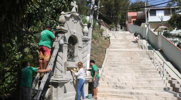 quatro pessoas em torno de um nicho junto à escadaria de morro. #paratodosverem