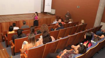 pessoas assistem palestra sentadas em auditório. #paratodosverem
