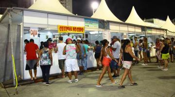 tendas para venda de lanches com pessoas circulando em torno. #paratodosverem 