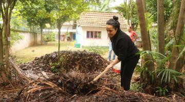 mulher está revolvendo material orgânico em jardim. #paratodosverem