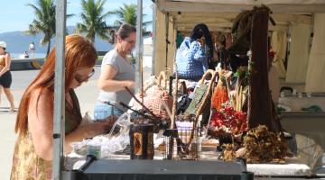 pessoas visualizam artigos em feira de economia criativa #paratodosverem