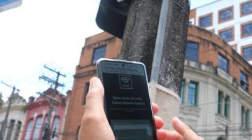 pessoa acessa internet com celular ao lado de placa #paratodosverem 