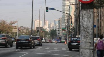 avenida com veículos circulando e semáforos todos em verde, abertos ao fluxo. #paratodosverem 
