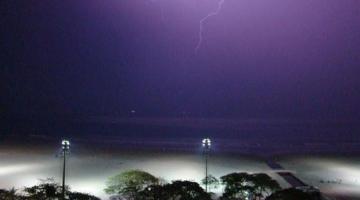 praia à noite com vista da faixa de arreia em primeiro plano e o mar ao fundo. Raios caem. #paratodosverem