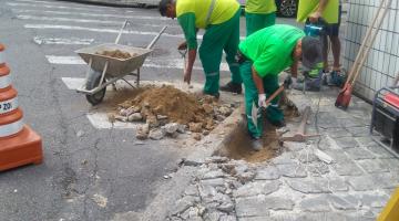 quatro homens estão trabalhando em esquina de rua, rebaixando a rua. #paratodosverem