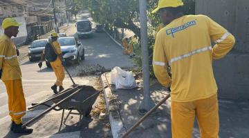 homens uniformizados estão varrendo material capinado de calçada e guia. #paratodosverem 