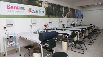 Sala com diversas macas de fisioterapia enfileiradas. Ao fundo há um painel onde se lê Santos Saudável. #Paratodosverem