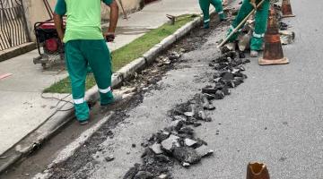 homens estão trabalhando na reconstrução de sarjeta. Trecho da rua junto à guia está quebrado. #paratodosverem