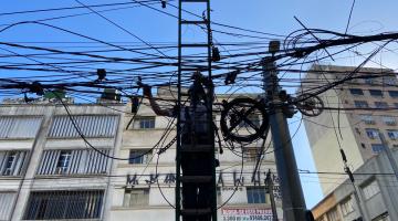 homem em escada remove fios aéreos. #paratodosverem
