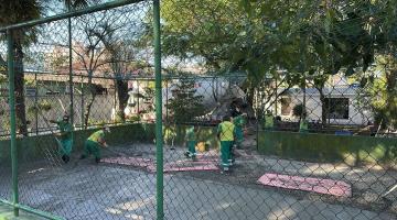 quadra com alambrado e homens trabalhando no interior. #paratodosverem