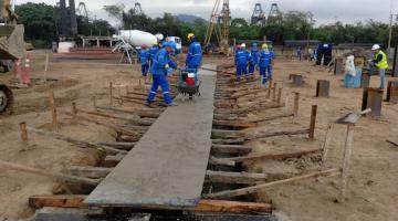 homens constroem estrutura em terreno. #paratodosverem