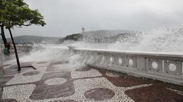 Ondas batendo em mureta da Ponta da Praia e água invadindo o calçadão. #paratodosverem