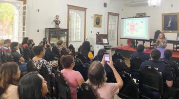 servidoras sentadas em auditório assistindo palestra. #paratodosverem