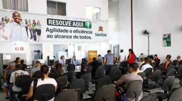 O salão do Resolve Aqui com diversas pessoas sentadas nos bancos aguardando atendimento. #Pracegover