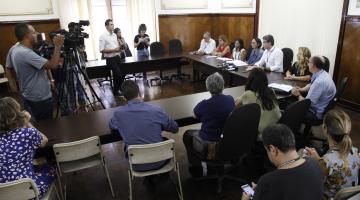 Reunião, com diversas pessoas sentada e cinegrafistas filmando. #paratodosverem