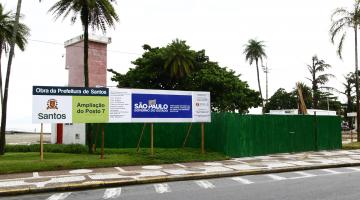 Área do posto de salvamento 7, na orla da praia, com tapume em torno da obra e placa informativa das melhorias. #Pracegover