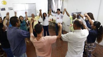 Alunos em círculo dão as mãos em atividade do curso #pracegover 