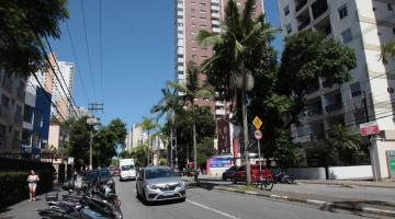 imagem da avenida com carros, motos estacionadas e prédios ao fundo #paratodosverem