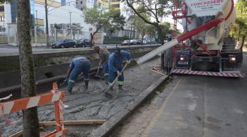 trabalhadores fazem concretagem em passeio ao lado de canal #paratodosverem