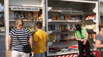 pessoas olham livros em biblioteca móvel na rua #paratodosverem