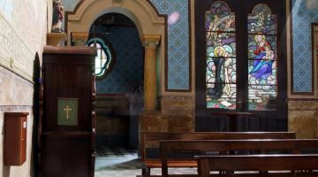 Interior da igreja do rosário, com bancos, paredes decoradas com azulejos e vitrais ao fundo. #paratodosverem