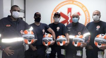 Condutores de motolâncias posam para fotos segurando capacetes. #Paratodosverem