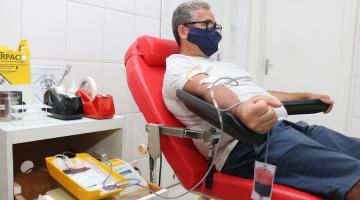 homem está sentado em poltrona. Ele está ligado pelo braço a uma bolsa de sangue. #paratodosverem