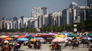 praia cheia com vários guarda-sóis #paratodosverem