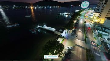 vista aérea da ponta da praia à noite, como o mar à esquerda, a avenida ao centro e os prédios à direito. Em primeiro plano, à esquerda, o deck do pescador. #paratodosverem