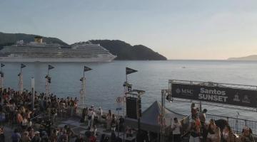 público na avenida de frente para o mar e navio ao fundo. #paratodosverem