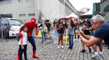 rapaz vestido de homem aranha abraça menino, enquanto ambos são fotografados #paratodosverem 