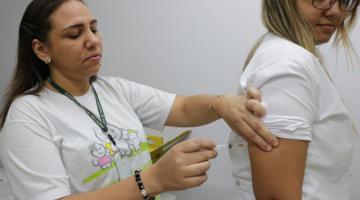Profissional de saúde aplica vacina em mulher. #pracegover