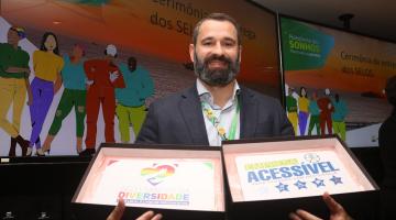 homem mostra os dois selos que a empresa ganhou #paratodosverem