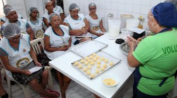 alunas assistem aula de panificação. pãezinhos crus estão sobre uma forma. #paratodosverem