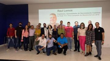 Pessoas posam para foto em cima do palco com telão ao fundo #paratodosverem