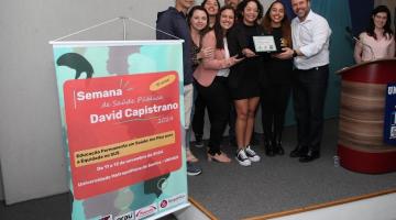 pessoas mostrando placa de prêmio #paratodosverem