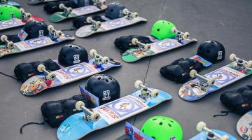 skates e capacetes dispostos no chão. #paratodosverem