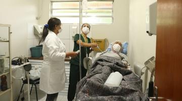 duas mulheres estão atendendo homem acabamado em hospital. #paratodosverem