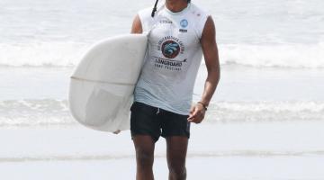 surfista segurando a prancha na praia #paratodosverem