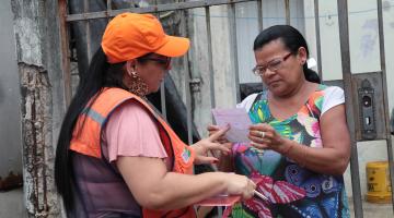 técnica da defesa civil entrega panfleto a mulher #pracegover 