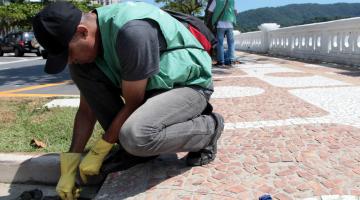 técnico da saúde coloca produto em ralo na orla #pracegover 