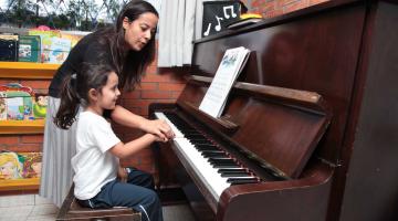 Voluntária ensina música a crianças em escola de Santos