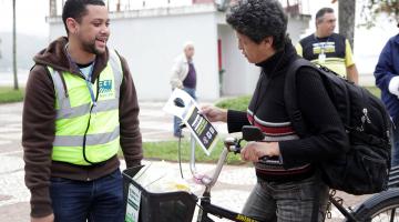 agente entrega folheto a ciclista #pracegover 