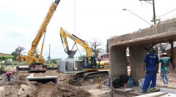 máquinas trabalham enquanto homem observa dentro de estrutura de concreto #paratodosverem 