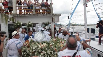 Imagem de Iemanjá está entrando em barco para iniciar procissão marítima. #Pracegover