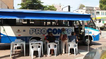 unidade móvel parada com pessoas sentadas em cadeiras na lateral #pracegover 