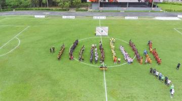 Equipes em filas dentro de campo de futebol na abertura do campeonato. #pratodosverem